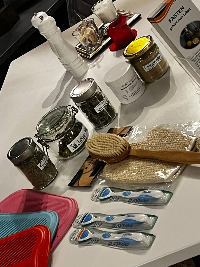 Tisch mit Fastenutensilien, Kräutergläsern und Pflegeartikeln