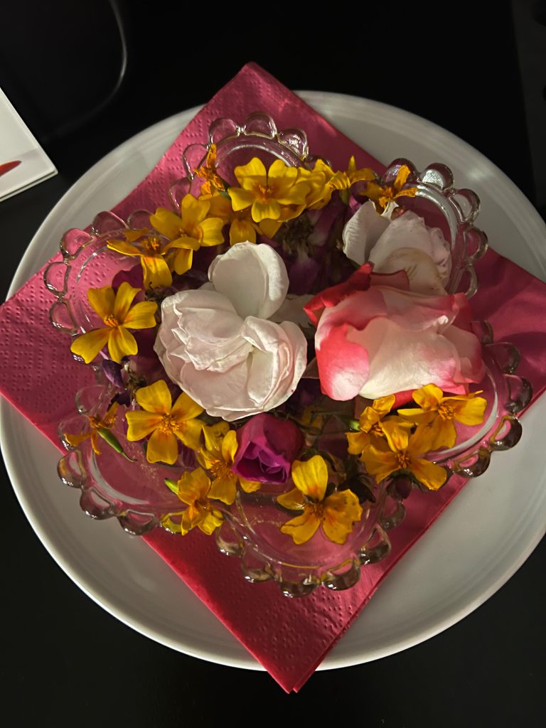 Glasschale mit bunten Blüten auf pinker Serviette